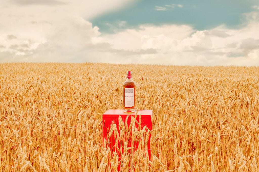 A bottle of Star Hill Farm Whisky 2026 in a wheat field