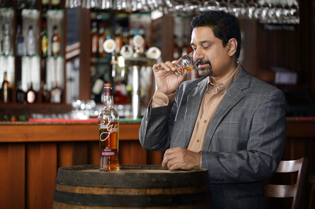 Paul John, the founder of Paul John whisky, noses Indian whisky in a bar