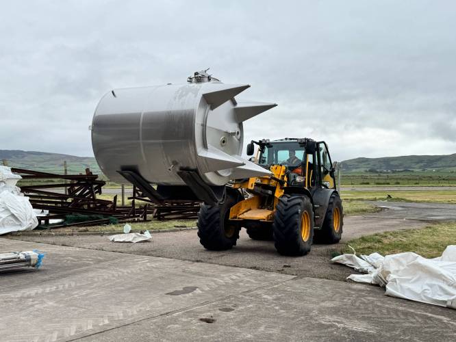 A digger takes distillery equipment to the Witchburn site