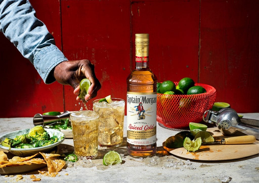 A bottle of Captain Morgan Spiced Gold among drinks and limes