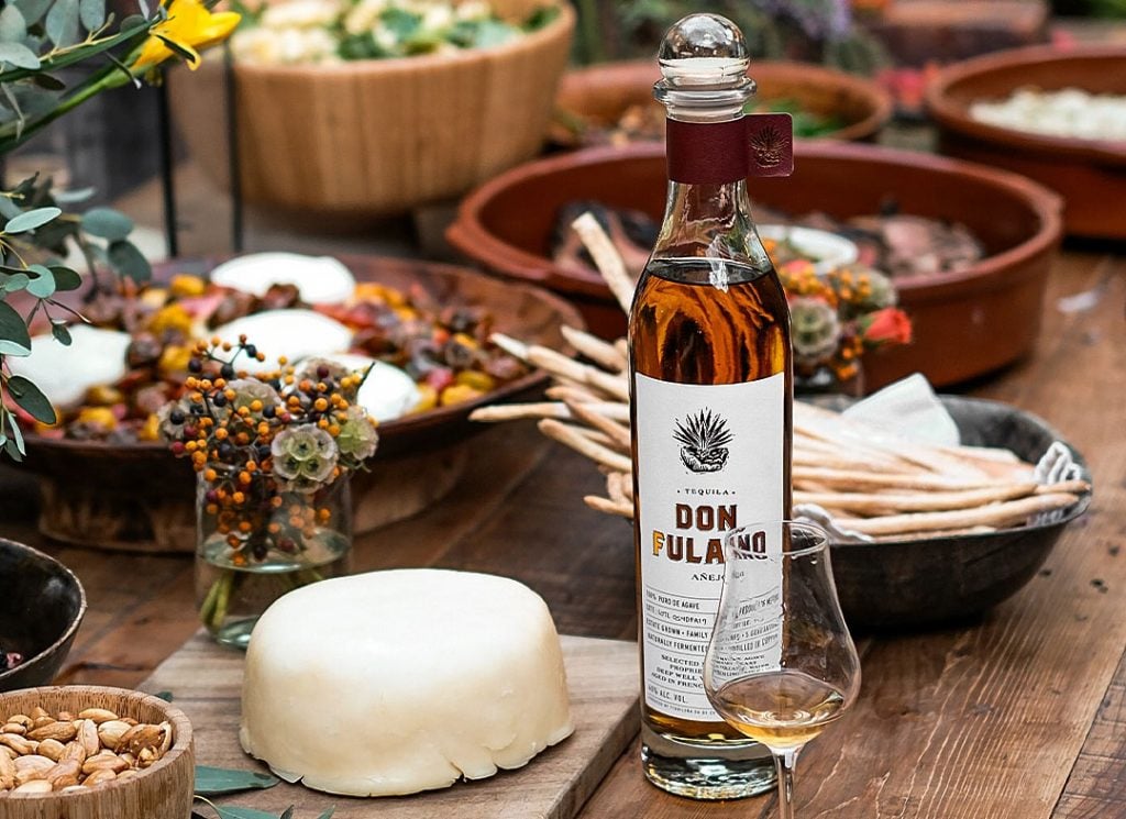 A bottle of Don Fulano Añejo on a table with food